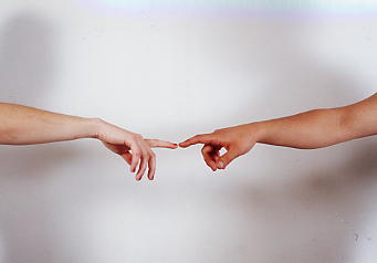 Two arms outstretched with fingers almost touching 